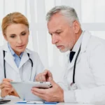 A man and woman in white coats examining a tablet, discussing facility billing services.